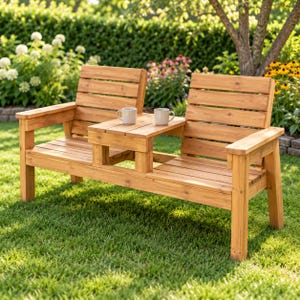 May include: A light brown wooden outdoor bench featuring two slatted seats connected by a central table. Two light-colored ceramic mugs are placed on the center table. The bench has armrests on both ends and a slatted backrest design.