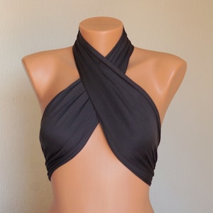May include: A black halter top made of stretchy fabric. The top is designed to be worn with a criss-cross front.