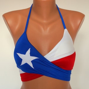May include: A blue, white, and red halter top with a white star on the blue section. The top is made of a stretchy fabric and has a wrap-around style.