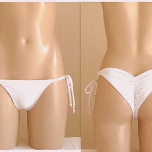 May include: White bikini bottom with adjustable ties on the sides. The bottom has a gathered detail at the back.