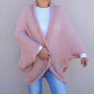 May include: A soft, pink knitted cardigan with a relaxed fit and long sleeves. The cardigan is open at the front and has a simple design.