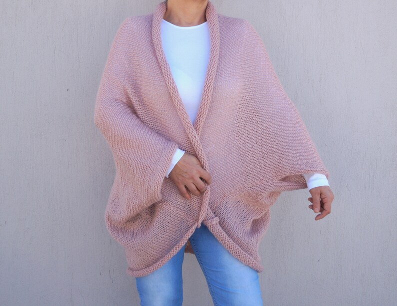 May include: A soft, pink knitted cardigan with a relaxed fit and long sleeves. The cardigan is open at the front and has a simple design.