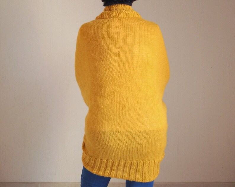 Puede incluir: Un su&eacute;ter largo de punto amarillo con cuello alto.