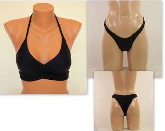 May include: Black bikini top with a halter neck and a wrap-around design. The bikini bottom is a high-cut style with a V-shaped front.