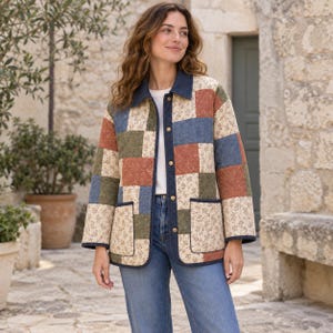 May include: A quilted jacket featuring a patchwork design of solid olive green, rust orange, and blue squares interspersed with cream-coloured floral print squares. The jacket has a dark blue collar, dark blue trim, and gold-tone metal snap buttons.