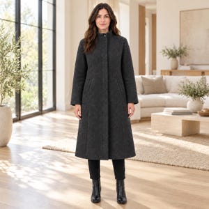 May include: A charcoal gray long coat featuring a high collar, a concealed front button placket, and long sleeves. The coat has a structured fit with vertical seam detailing and two side pockets, extending to a mid-calf length over black trousers.