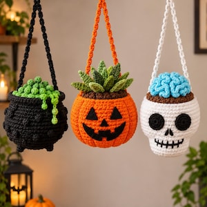 May include: Three hanging crochet planters featuring a black cauldron with green bubbles, an orange jack-o'-lantern with a green succulent, and a white skull with a blue brain, each suspended by a matching crocheted cord.