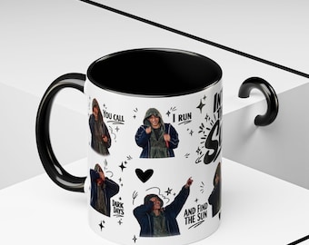 May include: A white ceramic mug with a black interior and handle, featuring a repeating graphic print of a person in a hooded jacket. The text reads: You call dark days, I run and find the sun. Includes black star and heart icons.
