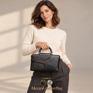 Könnte beinhalten: Eine schwarze Handtasche mit einem strukturierten, halbkreisförmigen Tragegriff und einer Kombination aus glatten und schlangenlederartigen Ledereinsätzen. Die Tasche zeigt ein geometrisches Design mit verschiedenen Abschnitten und den Text AlezanLeatherBag.