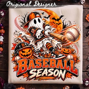 May include: A light-colored t-shirt featuring a graphic of a ghost wearing a baseball cap and uniform, swinging a wooden bat at a baseball. The design includes a large orange moon, bats, jack-o'-lanterns, and the text BASEBALL SEASON.