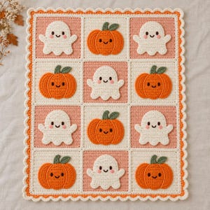 Puede incluir: Una manta de ganchillo rectangular con un patrón de cuadrícula de cuadrados alternos. Los cuadrados contienen fantasmas blancos y calabazas naranjas aplicados con caras sonrientes. La manta tiene un borde festoneado naranja y blanco.