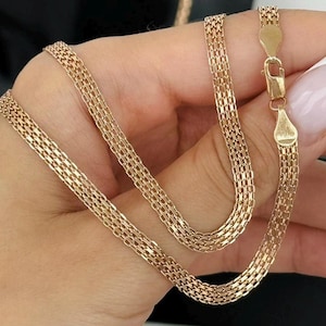 May include: A gold chain necklace featuring a woven mesh link design. The necklace is constructed with a repeating interlocking pattern and is secured with a polished gold lobster claw clasp at the end of the chain.