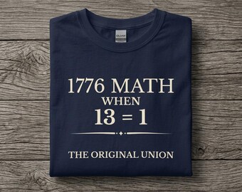 Könnte beinhalten: Ein dunkelblaues Kurzarm-T-Shirt mit cremefarbenem Text, der 1776 MATH WHEN 13 = 1 THE ORIGINAL UNION lautet. Das Shirt hat einen Rundhalsausschnitt und ein Gildan-Markenetikett, das am inneren Kragenbereich deutlich zu erkennen ist.