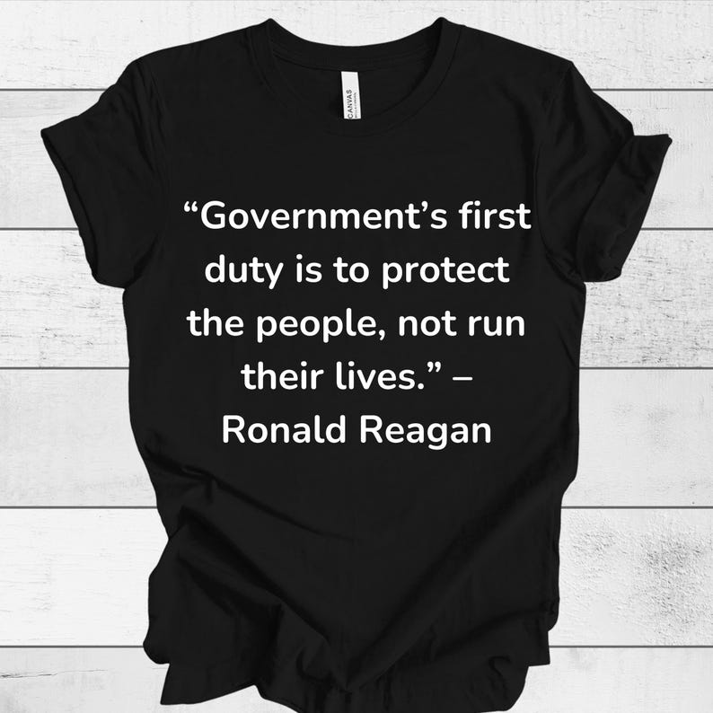 K&ouml;nnte beinhalten: Schwarzes T-Shirt mit wei&szlig;em Text, der lautet: "Die erste Pflicht der Regierung ist es, das Volk zu sch&uuml;tzen, nicht sein Leben zu f&uuml;hren." - Ronald Reagan