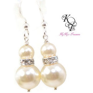May include: A pair of silver dangle earrings with two ivory pearls and a row of clear rhinestones on each earring.