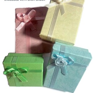 May include: Four small gift boxes with ribbon and a bow. The boxes are in different colors: pink, yellow, green, and blue.