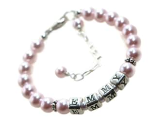May include: A pink pearl bracelet with a silver charm that spells out the name "EMMY".