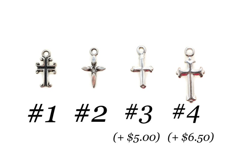 May include: Four silver-colored cross charms, each with a different design, are displayed against a white background. The crosses are labeled #1, #2, #3, and #4. The image includes text below the crosses.