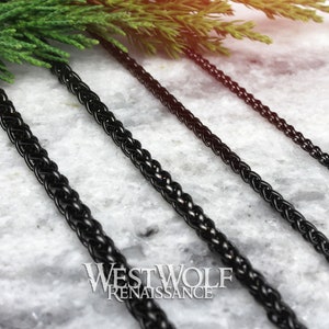 May include: Four black braided chains of different lengths on a white marble surface. The chains are made of metal and have a smooth, polished finish.