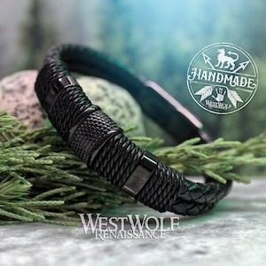 May include: Black leather bracelet with woven and textured details. The bracelet features a magnetic clasp and is accented with metal hardware. The image includes the text "HANDMADE" and "WESTWOLF RENAISSANCE".