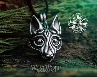 May include: Silver pendant featuring a detailed wolf head design with intricate Celtic knotwork. The pendant is on a black cord and is resting on a green mossy surface. The text "Handmade" is visible in the background.