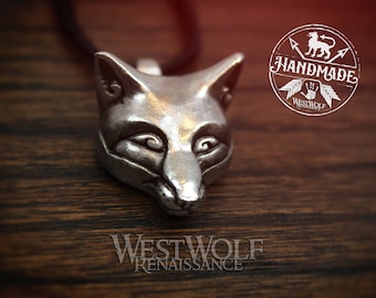 May include: A silver fox head pendant necklace. The pendant is detailed and realistic. The necklace is on a brown wooden surface. The image also includes a logo that says "Handmade Westwolf Renaissance".