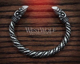 May include: A silver bracelet with a twisted rope design and bird head terminals. The bracelet is on a wooden surface.