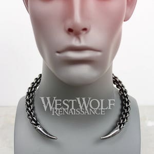 May include: A silver-toned metal choker necklace with two pointed ends. The necklace is on a mannequin's neck. The text "Westwolf Renaissance" is visible below the necklace.