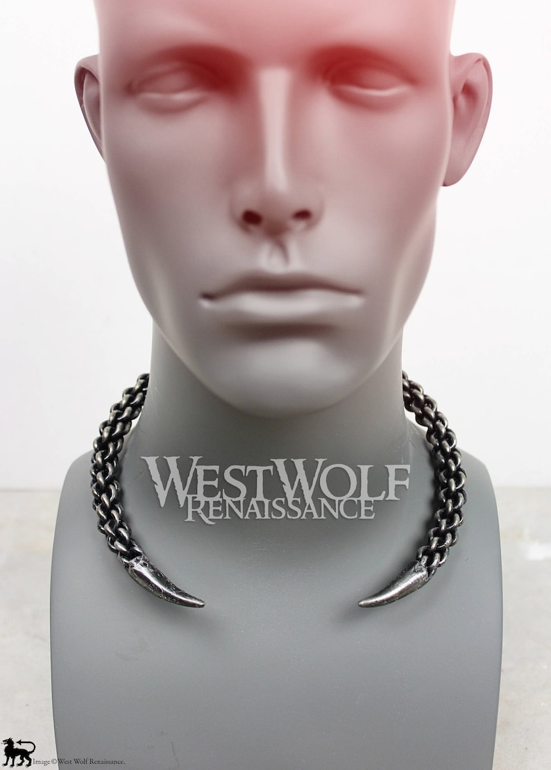 May include: A silver-toned metal choker necklace with two pointed ends. The necklace is on a mannequin's neck. The text "Westwolf Renaissance" is visible below the necklace.
