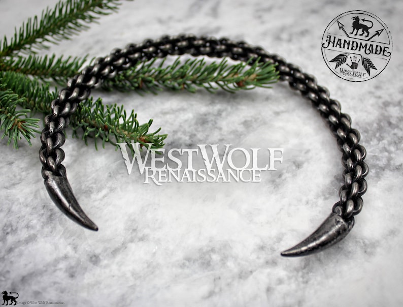 May include: A silver metal choker necklace with two pointed ends. The necklace is made of a braided chain design. The necklace is handmade and is called "Westwolf Renaissance".