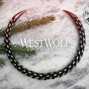 May include: A silver chain necklace with two pointed ends. The chain is made of interwoven links and has a dark oxidized finish. The necklace is handmade and has a Westwolf Renaissance logo tag.