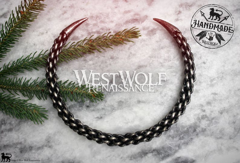 May include: A silver chain necklace with two pointed ends. The chain is made of interwoven links and has a dark oxidized finish. The necklace is handmade and has a Westwolf Renaissance logo tag.