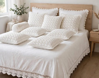 Può includere: Un set da letto bianco composto da un copripiumino e diversi cuscini decorativi, tutti decorati con intricati bordi e motivi in pizzo all'uncinetto. Il set include cuscini quadrati e un cuscino cilindrico con dettagli all'uncinetto coordinati.
