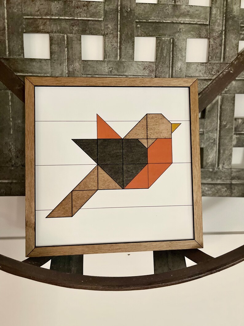 May include: A framed geometric art print of a bird with brown, black, and orange geometric shapes on a white background. barn quilt, handmade