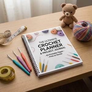May include: A spiral-bound planner titled The Ultimate Crochet Planner & Project Journal with 63 printable pages. The cover features colorful yarn balls and crochet hooks. Included are several metal crochet hooks and two yellow measuring tapes.