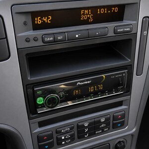 May include: A gray car dashboard center console featuring a Pioneer car stereo head unit with a digital display showing FM1 101.70. Above the stereo, a vehicle information display shows 16:42, 20 degrees Celsius, and FM1 101.70.
