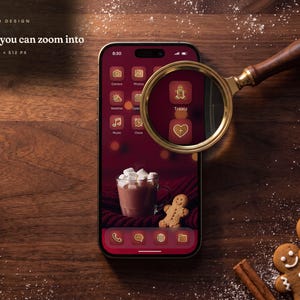 A brass magnifying glass with a walnut handle over a phone on a walnut table, magnifying the Gingerbread Classic gingerbread man icon to show its icing detail.