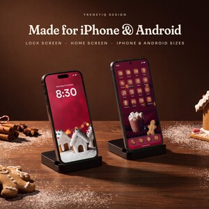 Gingerbread Classic on iPhone and Android: an iPhone shows the snowy iced gingerbread village lock screen at 8:30 and an Android phone shows the home screen with cranberry red gingerbread icons, both in black stands on a walnut table with gingerbread cookies and cinnamon.
