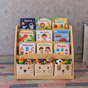 May include: A light-colored wooden bookshelf with three shelves holding nine children's books titled Space, Wild Animals, Fruits and Vegetables, Dinosaurs, My Body, Transport, Alphabet ABC, Good Manners, and Shapes, plus three animal-themed storage bins.