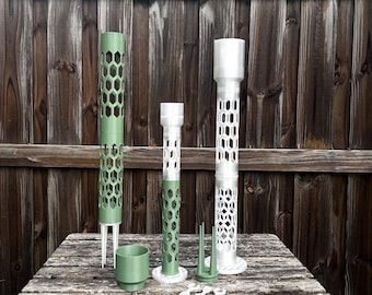May include: A collection of modular plant support poles featuring a hexagonal honeycomb pattern. The set includes two tall cylindrical structures in sage green and white, a small green cup, a green base with three prongs, and three small white clips.