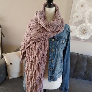 May include: A mauve knitted scarf with a lacy pattern draped over a mannequin wearing a denim jacket.