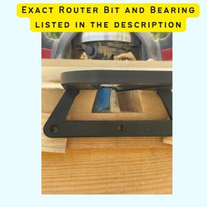 May include: A close-up of a router bit and bearing attached to a router. The router bit is cutting a groove in a piece of wood. The bearing is guiding the router bit along the edge of the wood.
