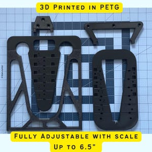 May include: A black 3D printed phone stand with adjustable height, printed in PETG plastic. The stand is fully adjustable with a scale up to 6.5 inches.