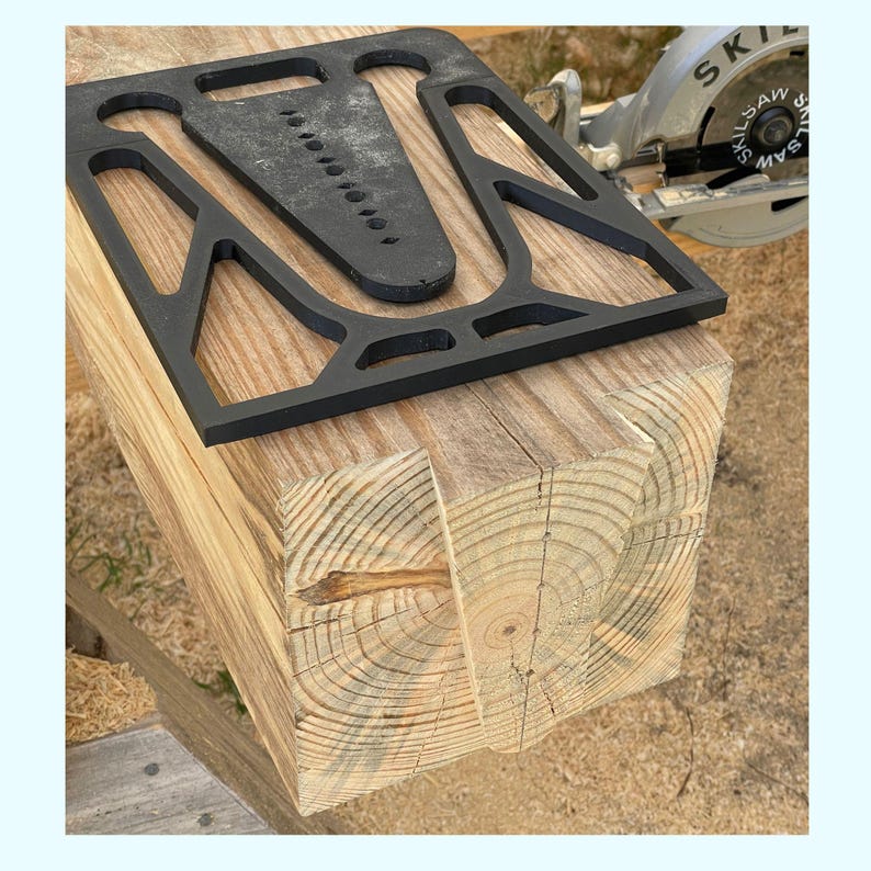 May include: A black plastic jig with multiple holes for use with a circular saw to cut precise angles in wood. The jig is placed on top of a wooden beam.