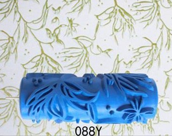 May include: Blue paint roller with a floral design. The roller is made of plastic and has a textured surface. The design is of leaves and flowers.