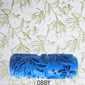 May include: Blue paint roller with a floral design. The roller is made of plastic and has a textured surface. The design is of leaves and flowers.