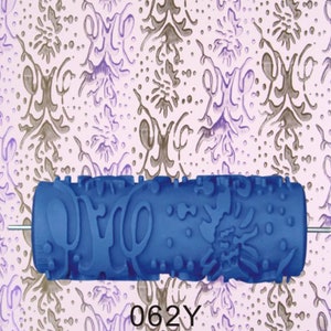 May include: Blue paint roller with a decorative pattern. The pattern includes swirls, dots, and abstract shapes. The roller is 6 inches long and has a metal rod attached to the side. The roller is labeled "062Y".