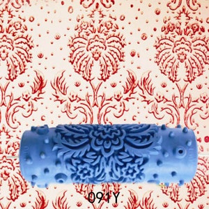 May include: Blue paint roller with a detailed floral pattern. The roller is designed to create a decorative effect on walls.
