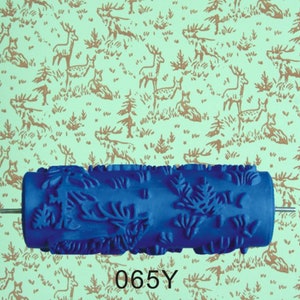 May include: Blue paint roller with a repeating pattern of stylized leaves and branches. The roller is 6.5 inches long and has a metal rod attached to the end. The roller is on a background of a repeating pattern of brown deer and trees on a light green background. The text "065Y" is printed on the background.