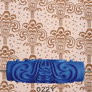 May include: Blue paint roller with a decorative pattern. The roller is designed to create a repeating pattern on walls. The pattern is similar to a stylized floral design. The roller is labeled "022Y".
